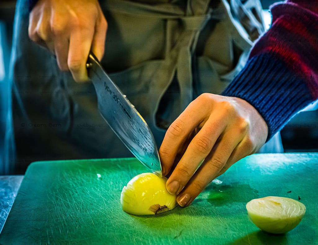 Laszlo Papdi macht das Kochmesser Chroma Type 301 fit für die erste Schneidübung. Der Klassiker steht an: die Zwiebel. Ob das Schneiden einer Zwiebel tränenreich oder tränenlos verläuft, hängt maßgeblich von der Schneidetechnik und der Schärfe eines Messers ab / © Foto: Georg Berg