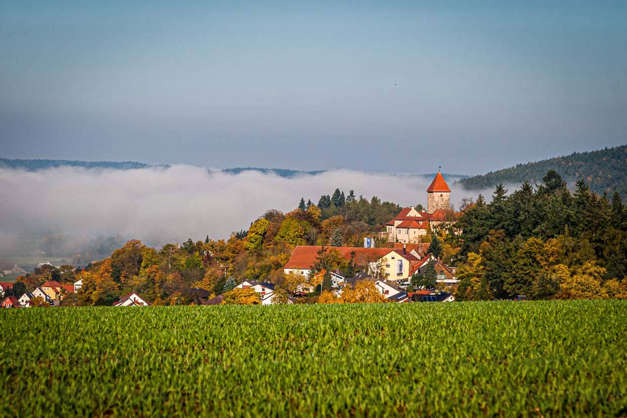 El verde paisaje de colinas del Alto Palatinado y en medio de él, entre la bruma matinal, el castillo de Wernberg / © Foto: Georg Berg