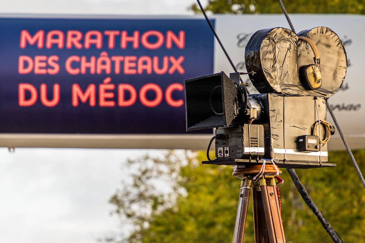Das Motto des 36. Marathon des Chateaux du Medoc lautet Film, da dürfen Accessores wie Filmkameras nicht fehlen. Aus den Lautsprechern schallt berühmte Filmmusik / © Foto: Georg Berg